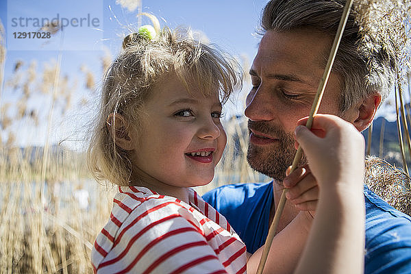 Portrait of father carrying daughter in reeds at the lakeshore