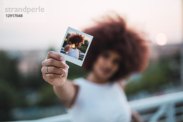Young woman showing instant photo of herself  close-up