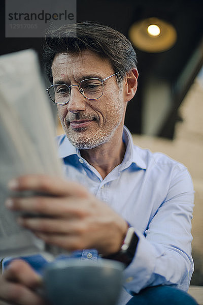 Businessman sitting in coffee shop  reading newspaper  drinking coffee