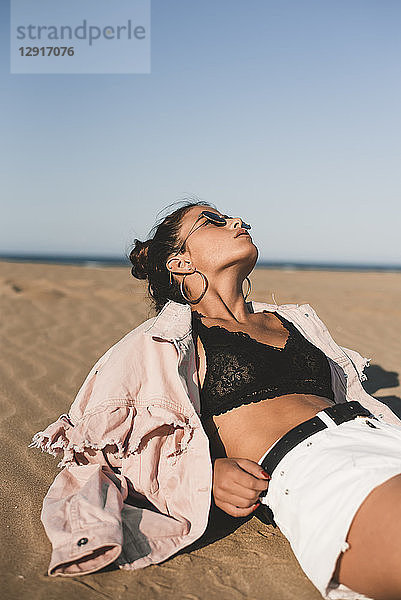 Fashionable teenage girl lying on the beach