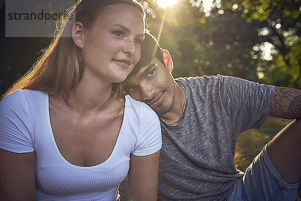 Romantic young couple sitting in park  enjoying sunset