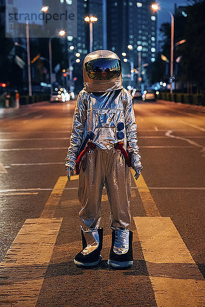 Spaceman standing on a street in the city at night
