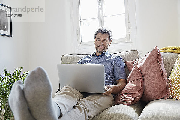 Man sitting on couch at home  using laptop