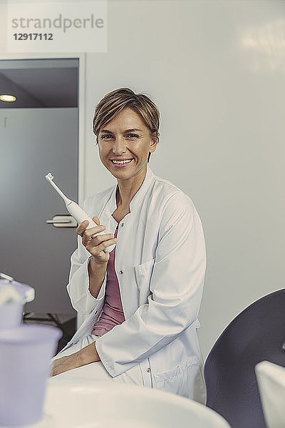 Female dentist holding electrical tooth brush