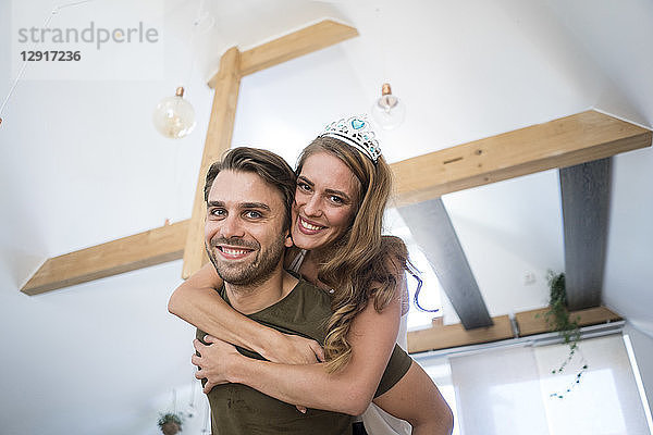 Portrait of happy couple at home with woman wearing tiara
