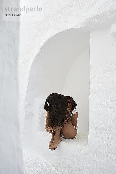Young woman crouching in a wall niche