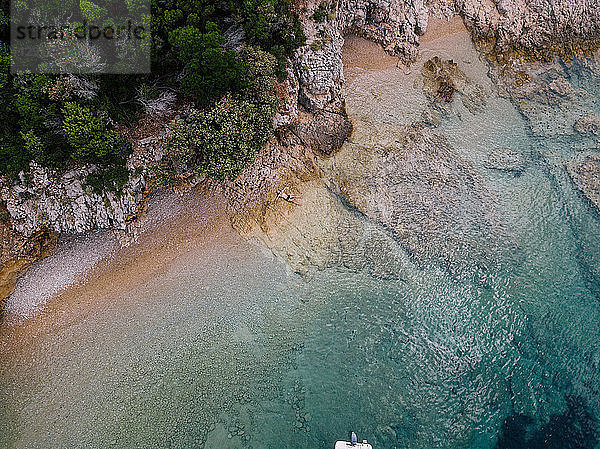 Croatia  Cres  Adriatic Sea  man lying on the rocky beach  aerial view