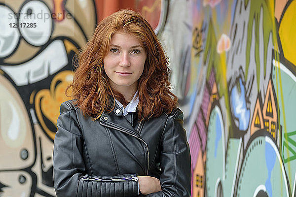 Italy  Finale Ligure  portrait of redheaded teenage girl wearing black leather jacket in front of mural