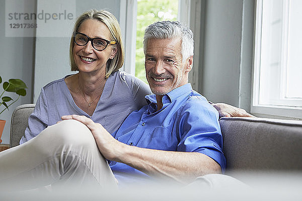 Portrait of smiling mature couple on couch at home