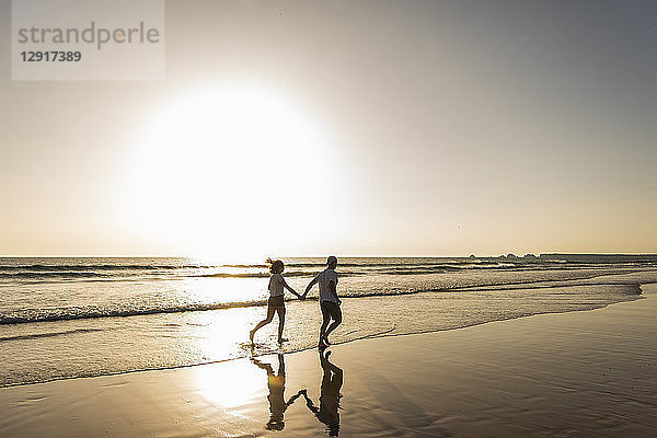 Young couple doing a romantic beach stroll at sunset