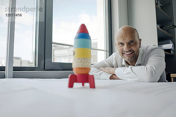 Businessman playing with toy rocket in office
