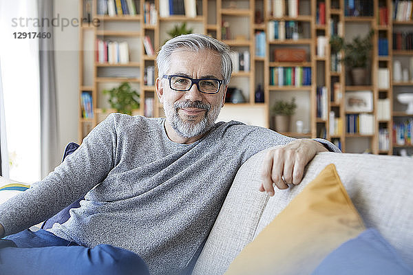 Portrait of smiling mature man relaxing on couch at home