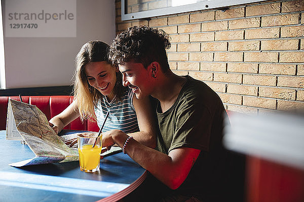 Smiling young couple sitting at table in a cafe with map