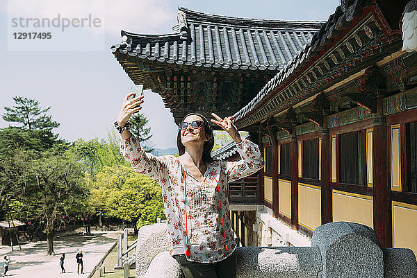 South Korea  Gyeongju  happy woman taking a selfie with cell phone in Bulguksa Temple