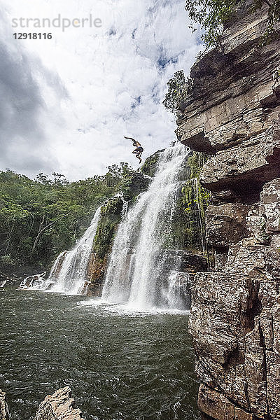 Blick auf einen abenteuerlustigen Mann  der von einem Wasserfall im Cerrado springt  Chapada dos Veadeiros  Goias  Brasilien
