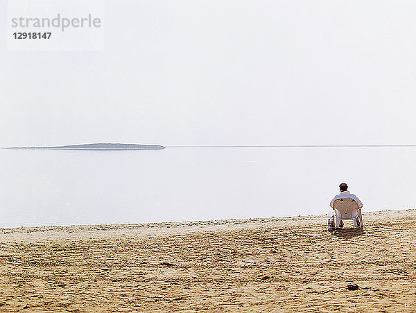Rückansicht eines einzelnen Mannes auf einem Stuhl am Ufer des Toten Meeres  Israel