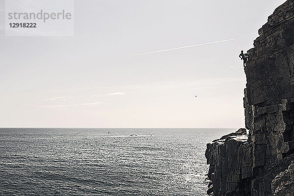 Mann klettert auf Otter Cliffs mit Blick auf das Meer  Acadia National Park  Maine  USA