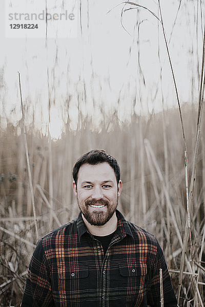 Lächelnder junger Mann im Flanellhemd vor einem Schilfgürtel  Portland  Maine  USA