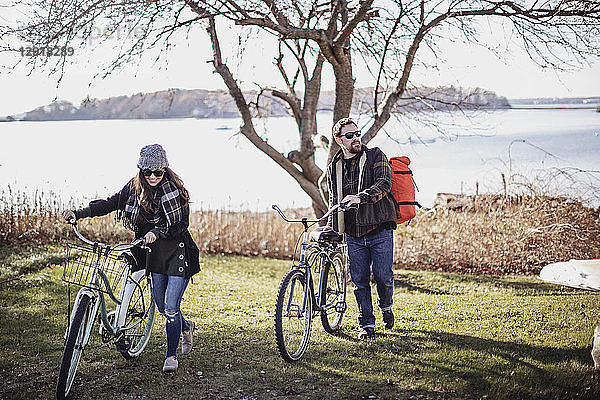 Paar  das mit dem Fahrrad über eine Wiese fährt  mit dem Meer im Hintergrund  Peaks Island  Maine  USA