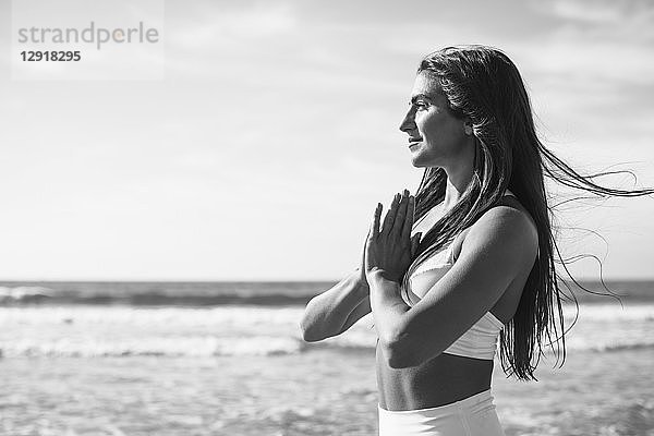 Seitenansicht einer jungen Frau beim Yoga am Strand