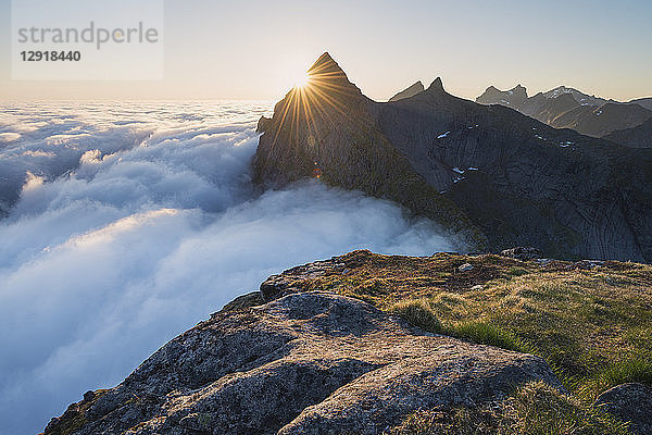 Majestätische Naturlandschaft mit dem Gipfel Helvetestind über dem Nebel  Moskenesoya  Lofoten  Norwegen
