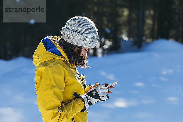 Seitenansicht einer jungen Frau beim Telefonieren im Freien im Winter  Whistler  British Columbia  Kanada