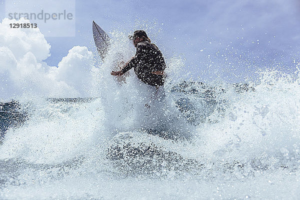 Männlicher Surfer spritzt beim Reiten einer Welle gegen den Himmel  Male  Malediven