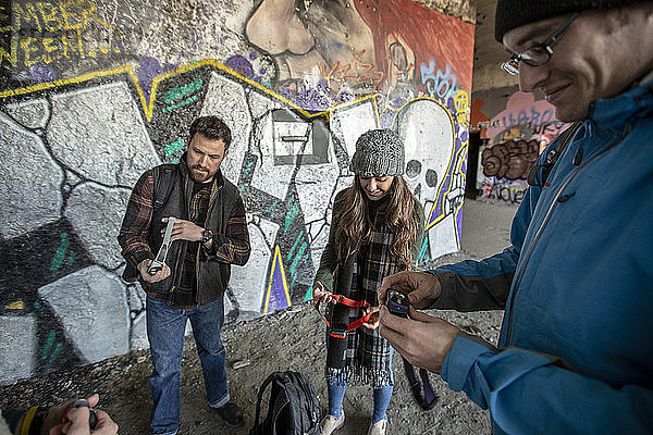Freunde verteilen Stirnlampen vor einer mit Graffiti beschmierten Wand  bevor sie einen verlassenen Bunker erkunden  Portland  Maine  USA