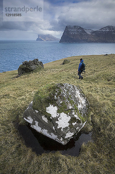 Fernblick auf einen Rucksacktouristen  der am Meer spazieren geht  Kalsoy  Färöer Inseln