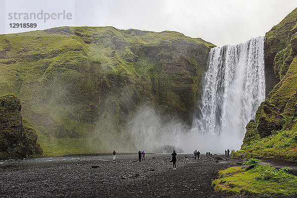 Touristen besuchen den Skogafoss  einen der berühmtesten Wasserfälle in Island. Der Wasserfall liegt in der NÃ?he des Highway One (auch als RingstraÃŸe bekannt) und stÃ?rzt sich 60 Meter in die Tiefe  und es gibt Pfade  die es Besuchern ermÃ¶glichen  bis zum FuÃŸ und zur Spitze des Wasserfalls zu gehen. Der Wasserfall befindet sich am Fluss Skoga  der durch das isländische Hochland fließt  bevor er den Atlantik erreicht.