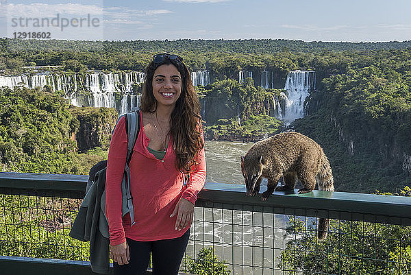 Porträt einer Touristin  die mit dem südamerikanischen Nasenbär Nasua vor den Iguazu-Fällen posiert  Parana  Brasilien