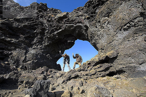 Zwei Männer beim Headbanging in einem natürlichen Felsbogen  Dimmuborgir  Myvatin  Island