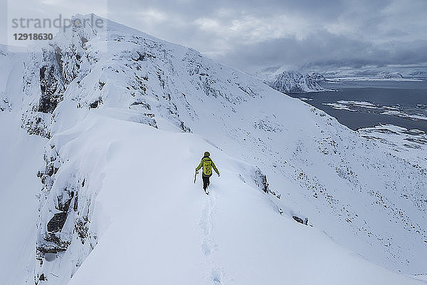 Fernsicht auf eine einzelne Wanderin beim Aufstieg zum Matmora-Gipfel im Winter  Austvagoy  Lofoten  Norwegen