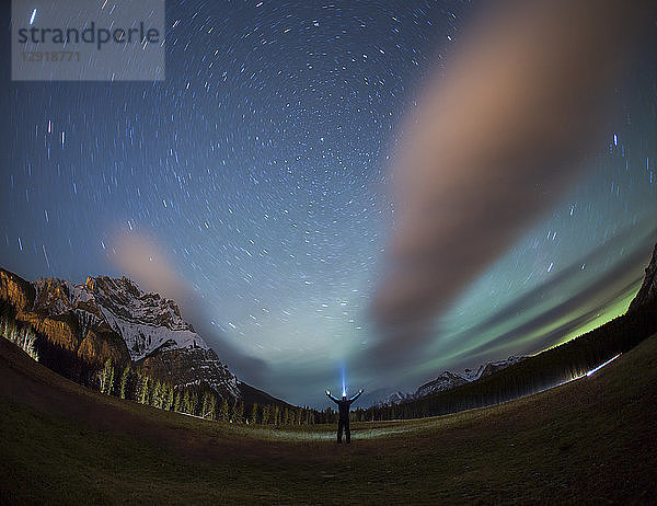 Silhouette einer Person mit Stirnlampe und erhobenen Armen unter nächtlichem Sternenhimmel  Banff National Park  Alberta  Kanada