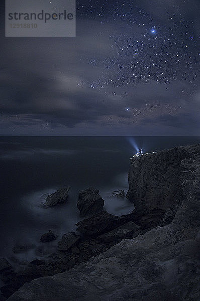 Person leuchtet mit einer Taschenlampe in den nächtlichen Himmel an einer Küstenklippe  Kauai  Hawaii-Inseln  USA