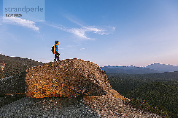 Seitenansicht einer einsamen Wanderin  die auf einem Felsblock steht  Pitchoffâ€ Mountain  Adirondack Mountains  New York State  USA