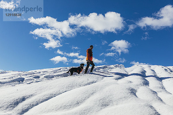 Wolken über einem Schneeschuhwanderer mit Hund auf einem schneebedeckten Berg  Whistler  British Columbia  Kanada