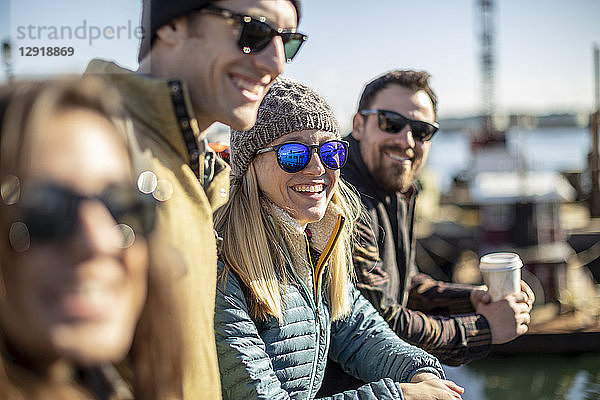 Porträt einer jungen Frau mit Sonnenbrille  die lachend mit Freunden am Hafen wartet  Portland  Maine  USA