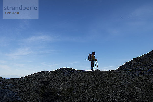 Seitenansicht einer einzelnen Wanderin  die auf einem Bergkamm steht  Moskenesoya  Lofoten  Norwegen