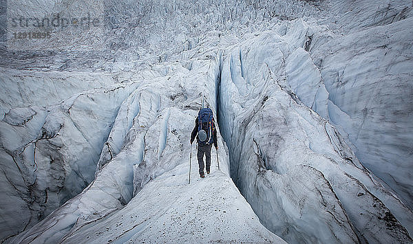 Rückansicht eines männlichen Rucksacktouristen  der beim Aufstieg zum Mount Robson über einen Gletscher wandert  British Columbia  Kanada