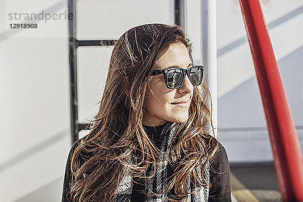Porträt einer lächelnden attraktiven jungen Frau mit Sonnenbrille auf einer Fähre