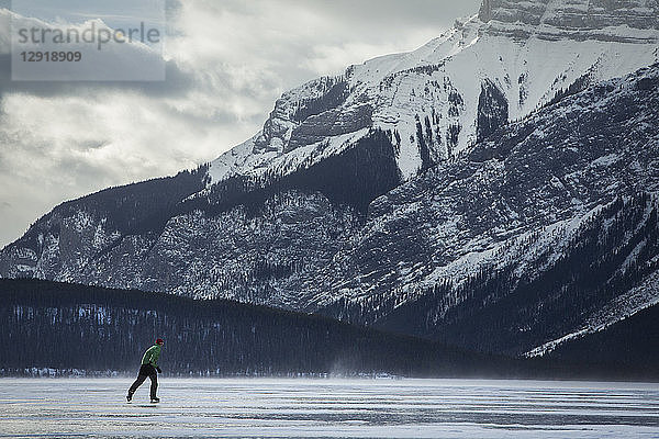 Seitenansicht eines Mannes beim Schlittschuhlaufen auf dem zugefrorenen Lake Minnewanka im Winter  Banff National Park  Alberta  Kanada