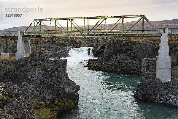 Wanderin beim Überqueren einer Brücke über einen Fluss  Island