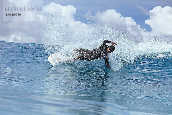 Männlicher Surfer  der sich beim Reiten auf einer Welle gegen die Wolken neigt  Male  Malediven