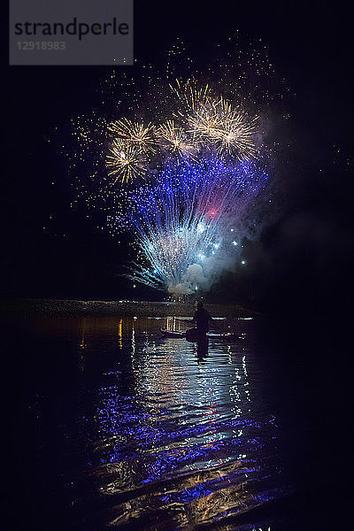 Feuerwerk im Hintergrund mit Silhouette von Paddelboarder auf Long Lake 4. Juli bei Nacht  New York  USA