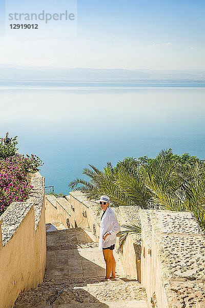 Frau steht auf einer Steintreppe  die zum Toten Meer führt  und schaut zurück in Richtung Kamera  Amman  Jordanien