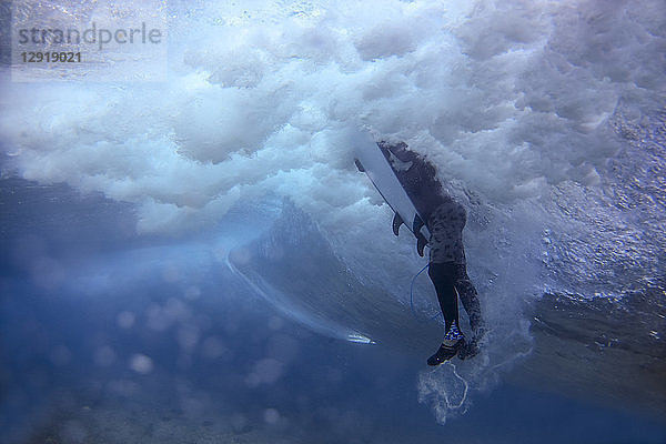 Unterwasseransicht eines männlichen Surfers  der im Meer schwimmt  Male  Malediven