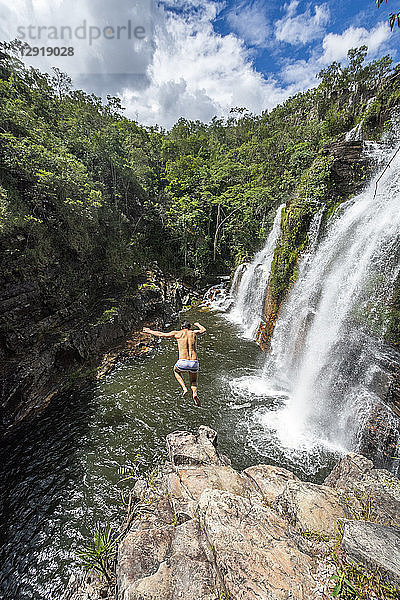 Blick auf einen abenteuerlustigen Mann  der von einem Wasserfall im Cerrado springt  Chapada dos Veadeiros  Goias  Brasilien