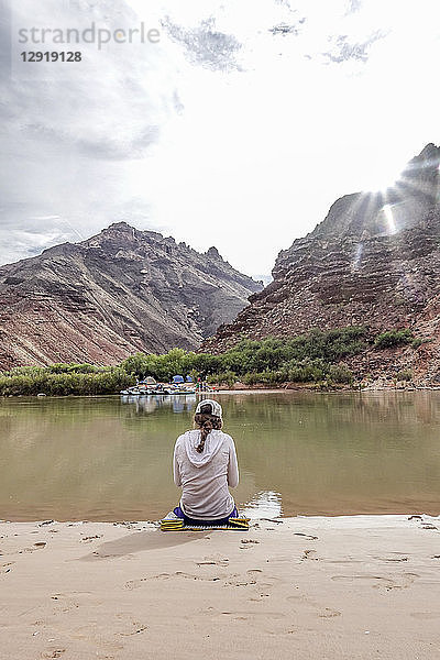 Rückansicht einer Wanderin  die am Ufer des Colorado River im Grand Canyon  Arizona  USA  sitzt