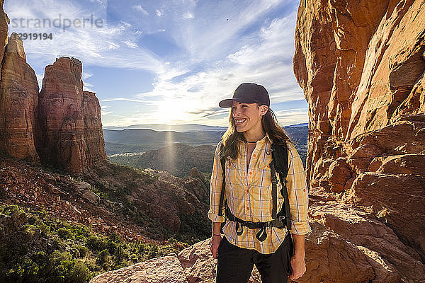 Porträt einer Wanderin  die am Cathedral Rock steht und lächelt  mit untergehender Sonne im Hintergrund  Arizona  USA